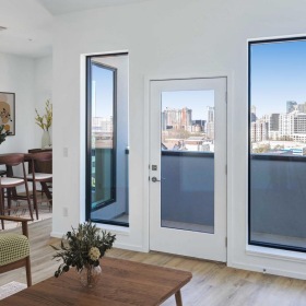 a living room with large windows, tables and chairs
