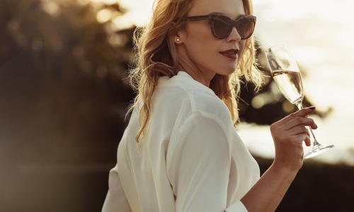 a woman sipping on wine outdoors in a bright dress